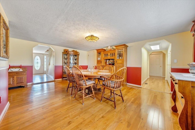 dining space with a textured ceiling and light hardwood / wood-style flooring