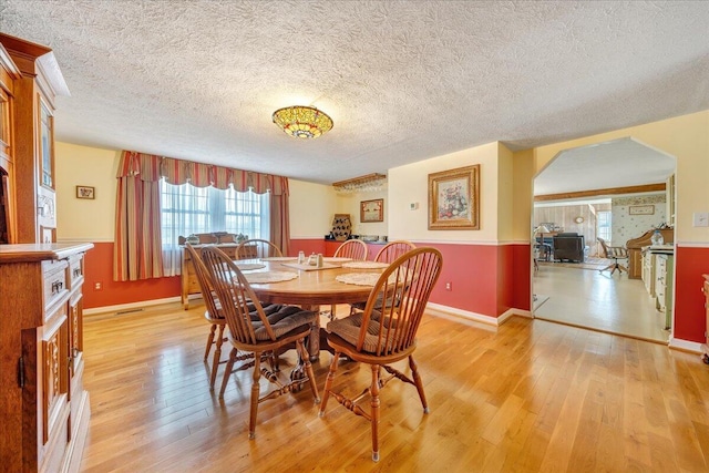 dining space with a textured ceiling, a fireplace, and light wood-type flooring