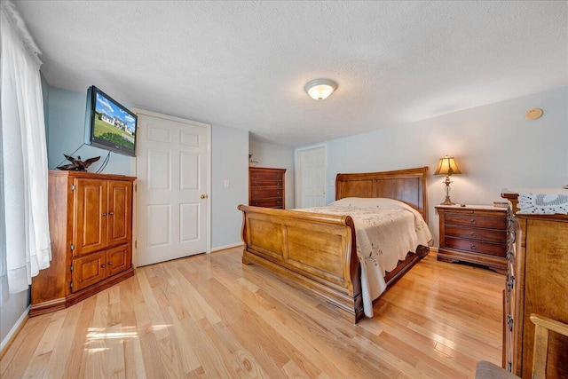 bedroom with a textured ceiling and light wood-type flooring