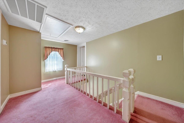 hall with light carpet and a textured ceiling