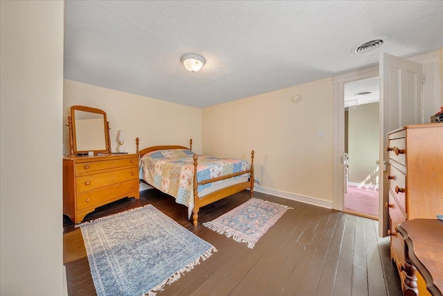 bedroom with a textured ceiling and dark wood-type flooring