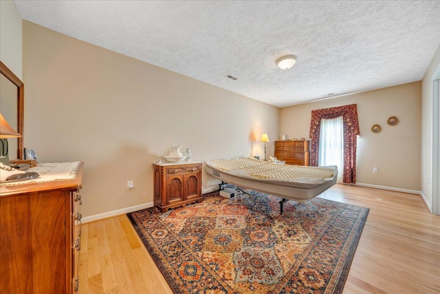 bedroom with light hardwood / wood-style floors and a textured ceiling