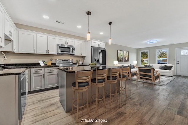 kitchen with white cabinetry, sink, pendant lighting, a kitchen island, and appliances with stainless steel finishes