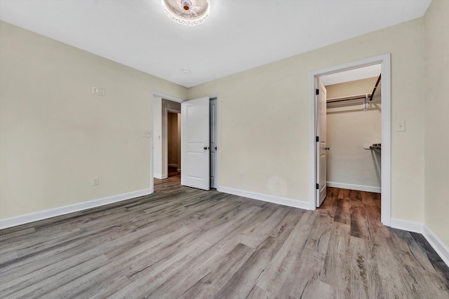 unfurnished bedroom featuring light hardwood / wood-style flooring, a spacious closet, and a closet