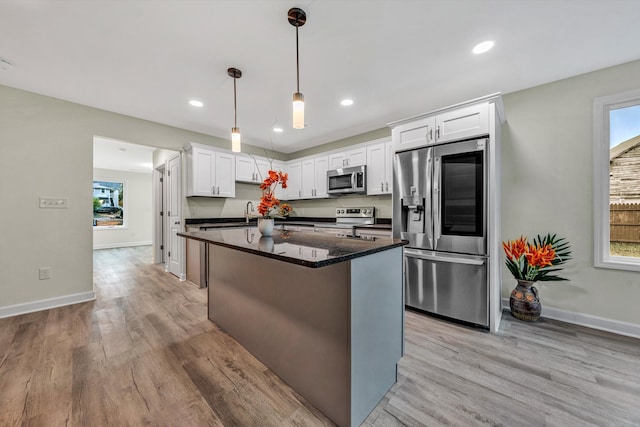 kitchen with pendant lighting, stainless steel appliances, white cabinetry, and light hardwood / wood-style flooring