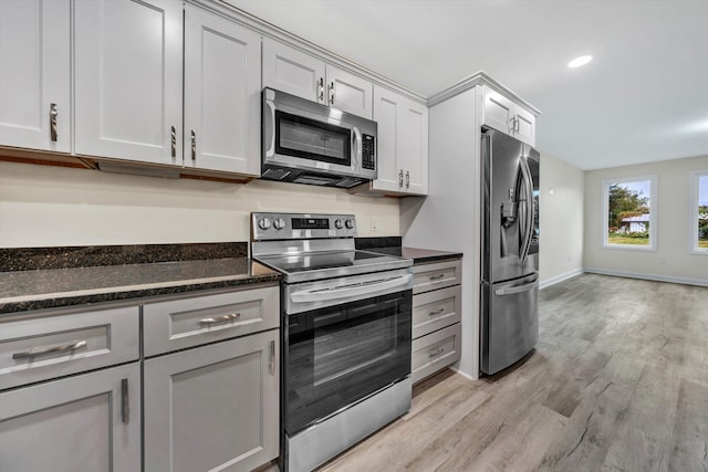 kitchen featuring appliances with stainless steel finishes, light wood-type flooring, gray cabinets, and dark stone countertops