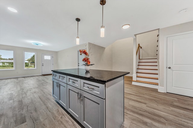 kitchen with gray cabinetry, a kitchen island, decorative light fixtures, and hardwood / wood-style flooring