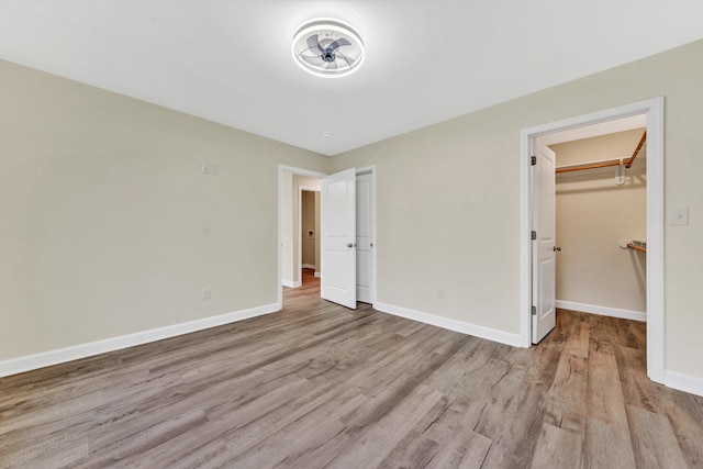 unfurnished bedroom featuring a spacious closet, light hardwood / wood-style flooring, and a closet