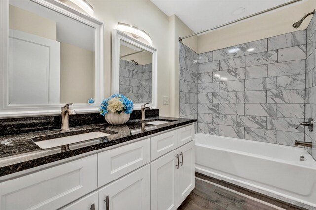 bathroom with hardwood / wood-style floors, vanity, and tiled shower / bath