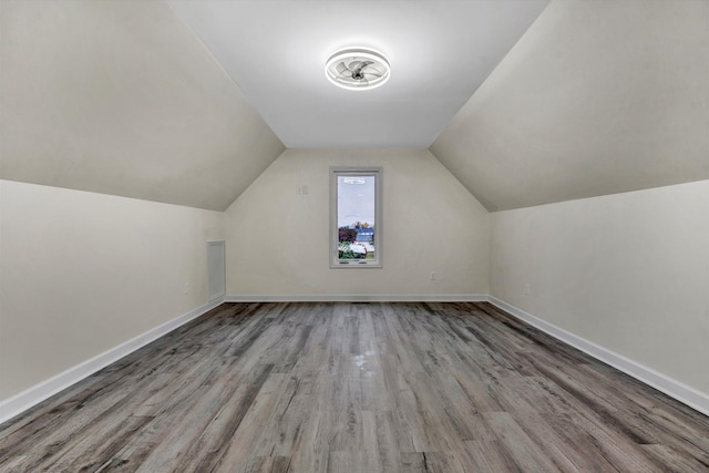 additional living space with light hardwood / wood-style flooring and vaulted ceiling