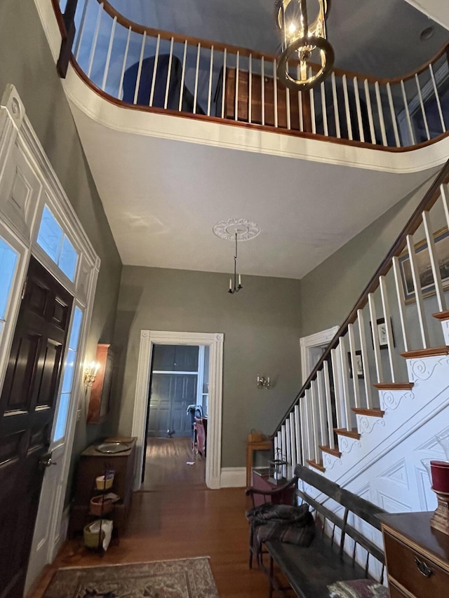 entrance foyer featuring a towering ceiling, dark wood-type flooring, and a notable chandelier