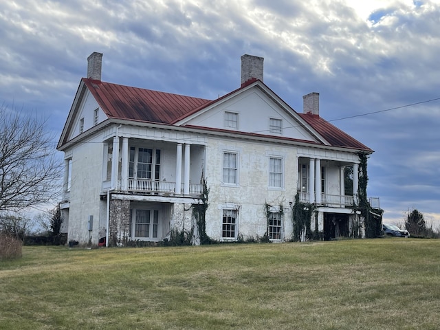 back of property with a lawn and a balcony