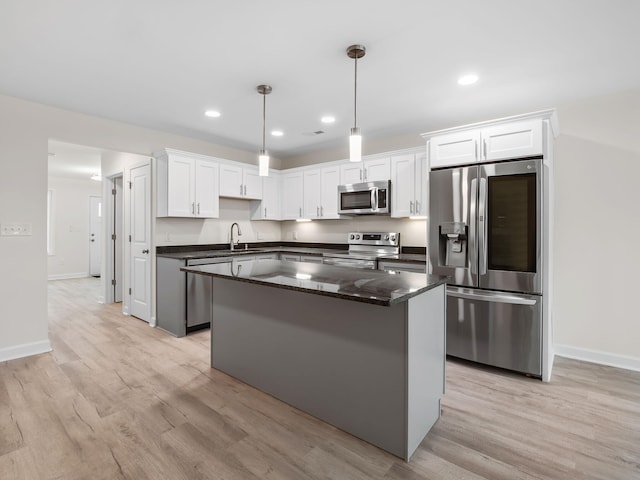 kitchen with light hardwood / wood-style flooring, white cabinets, a center island, hanging light fixtures, and appliances with stainless steel finishes