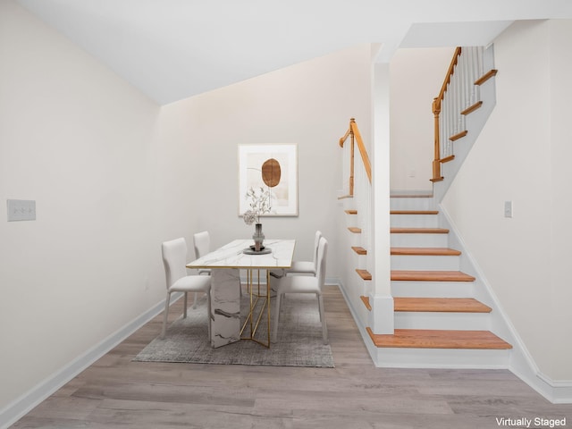 dining room with wood-type flooring and vaulted ceiling