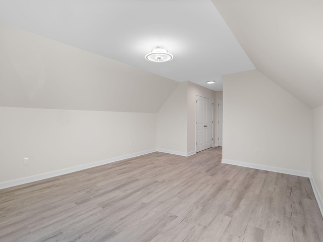 additional living space with vaulted ceiling and light wood-type flooring