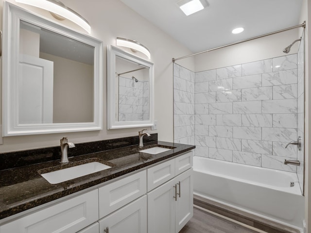 bathroom with wood-type flooring, dual vanity, and tiled shower / bath combo