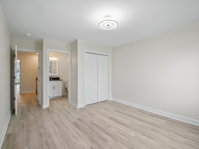 unfurnished bedroom featuring connected bathroom, light hardwood / wood-style flooring, and a closet