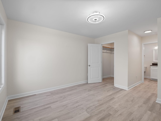 unfurnished bedroom with a closet, light wood-type flooring, and a walk in closet