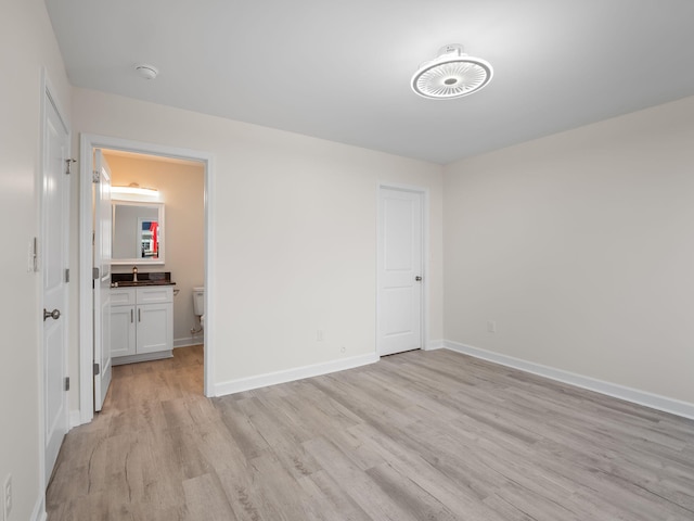 unfurnished bedroom with sink, light wood-type flooring, and connected bathroom