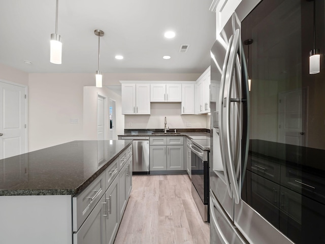 kitchen with light hardwood / wood-style flooring, stainless steel appliances, sink, a center island, and white cabinetry