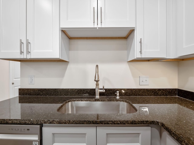 kitchen featuring dark stone counters, white cabinetry, dishwasher, and sink