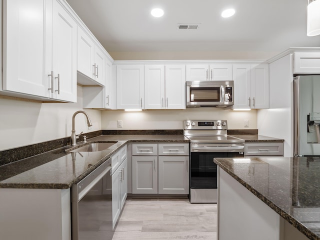 kitchen featuring white cabinets, light hardwood / wood-style flooring, appliances with stainless steel finishes, and sink