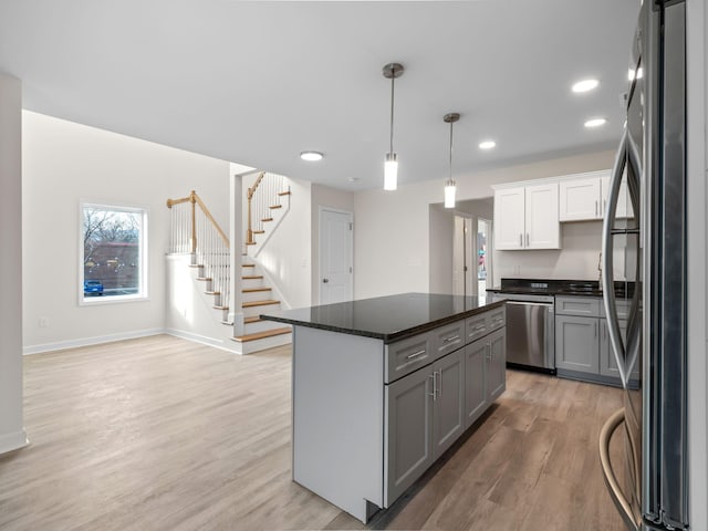 kitchen with pendant lighting, white cabinets, light hardwood / wood-style flooring, appliances with stainless steel finishes, and a kitchen island