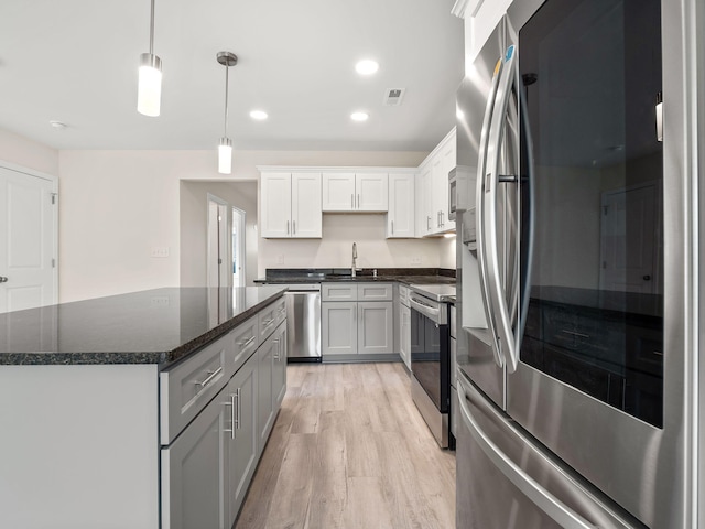 kitchen with sink, stainless steel appliances, light hardwood / wood-style floors, decorative light fixtures, and white cabinets