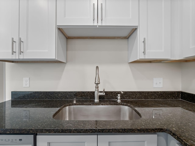 kitchen with dishwasher, sink, white cabinets, and dark stone counters