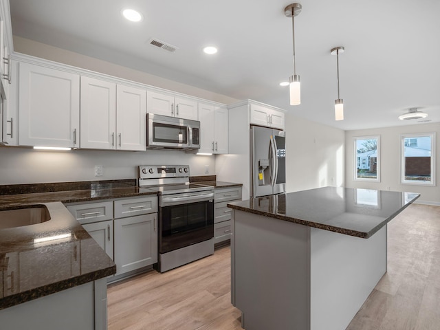 kitchen featuring white cabinets, a center island, stainless steel appliances, and light hardwood / wood-style floors