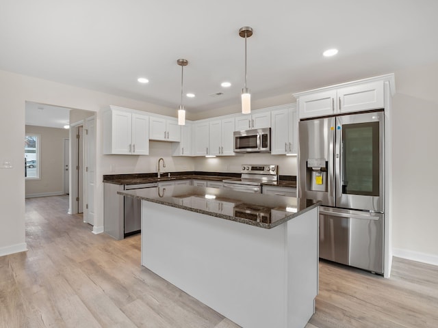 kitchen featuring a center island, white cabinets, hanging light fixtures, and appliances with stainless steel finishes