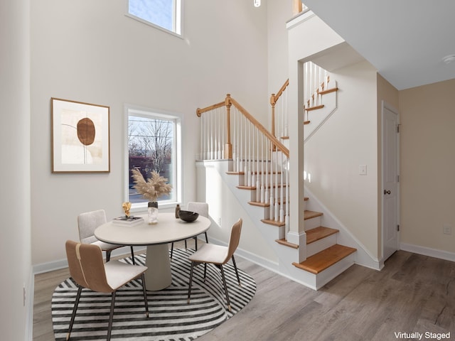 dining space featuring hardwood / wood-style floors and a towering ceiling