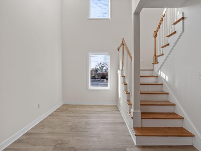 stairway with wood-type flooring and a towering ceiling