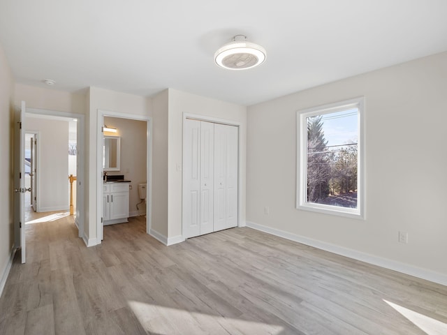 unfurnished bedroom featuring connected bathroom, light hardwood / wood-style floors, and a closet