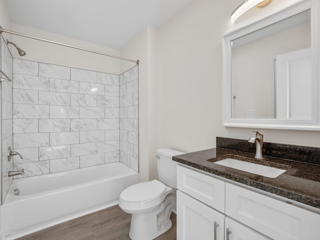 full bathroom featuring tiled shower / bath, vanity, wood-type flooring, and toilet