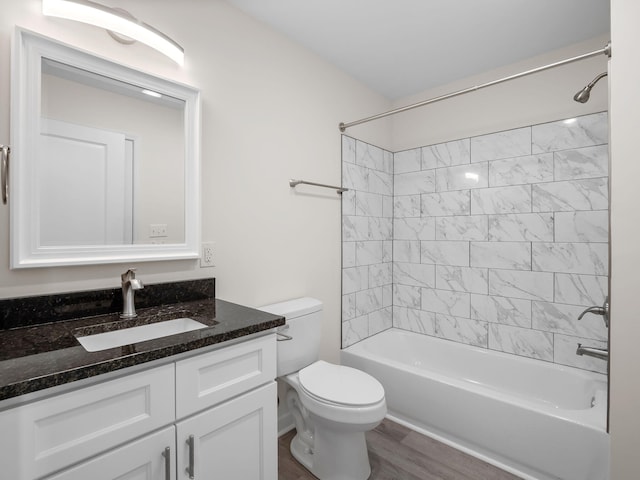 full bathroom featuring hardwood / wood-style flooring, vanity, toilet, and tiled shower / bath