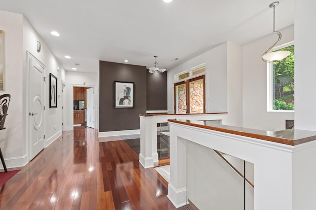 hallway with dark wood-type flooring and a chandelier