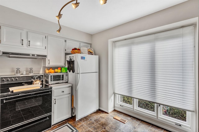 kitchen featuring dark tile flooring, white fridge, white cabinetry, and range with electric cooktop