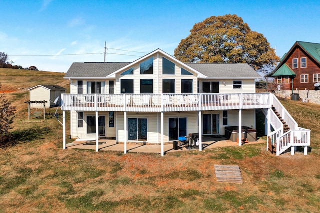 rear view of property featuring an outdoor structure, a lawn, and a patio area