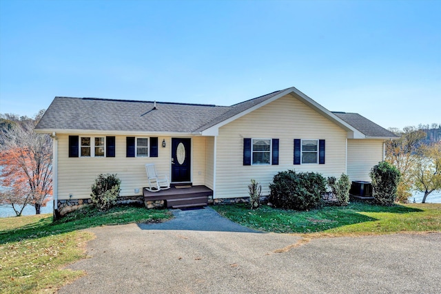 ranch-style home with a front lawn and central air condition unit