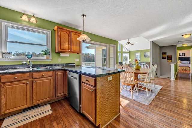 kitchen featuring stainless steel dishwasher, sink, dark wood-type flooring, and decorative light fixtures