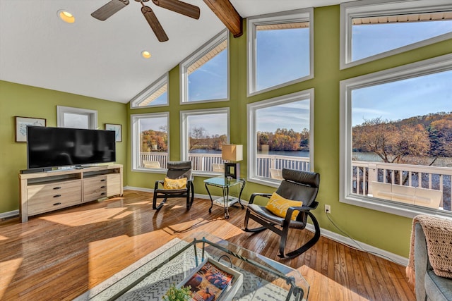 living room with ceiling fan, light hardwood / wood-style flooring, a water view, high vaulted ceiling, and beam ceiling