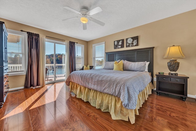 bedroom featuring dark hardwood / wood-style flooring, a textured ceiling, ceiling fan, and access to outside