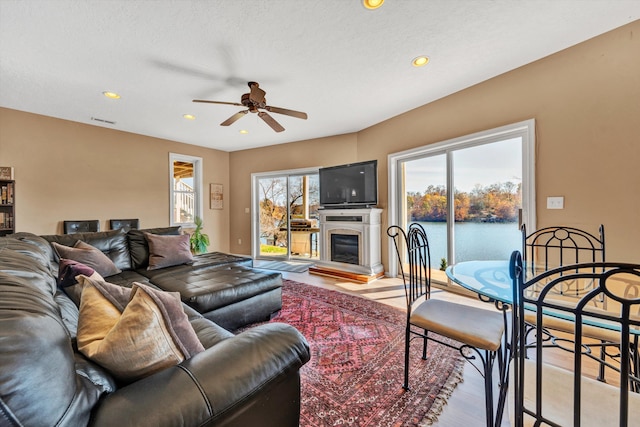 living room featuring ceiling fan, a water view, and light wood-type flooring