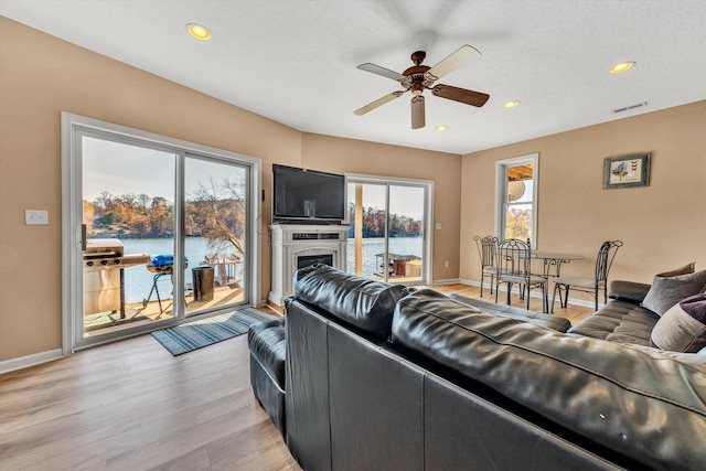 living room with a water view, ceiling fan, a healthy amount of sunlight, and light hardwood / wood-style flooring