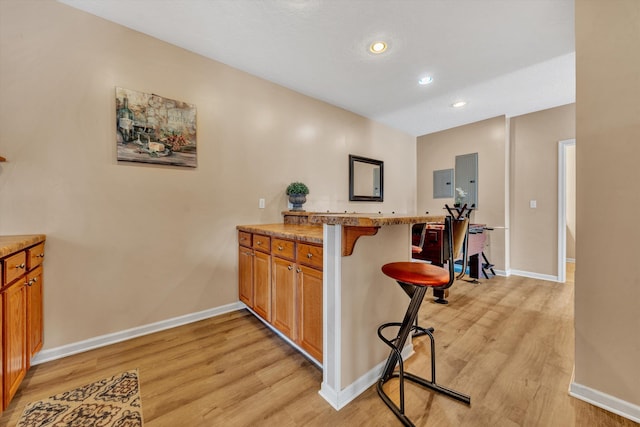 kitchen featuring a kitchen bar, light hardwood / wood-style floors, and kitchen peninsula