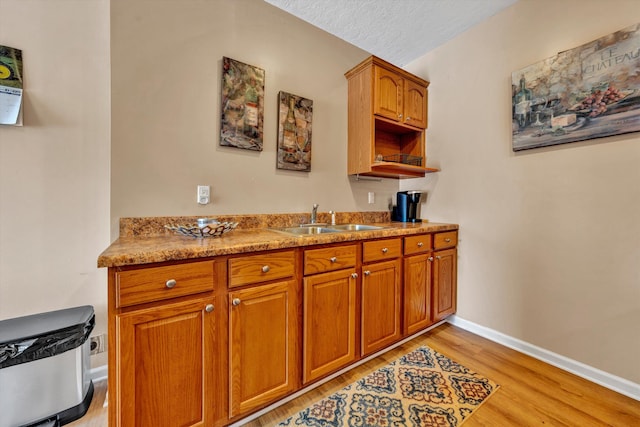 kitchen with light hardwood / wood-style flooring, sink, and light stone counters