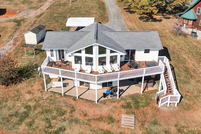 rear view of house featuring a patio, a wooden deck, and a lawn