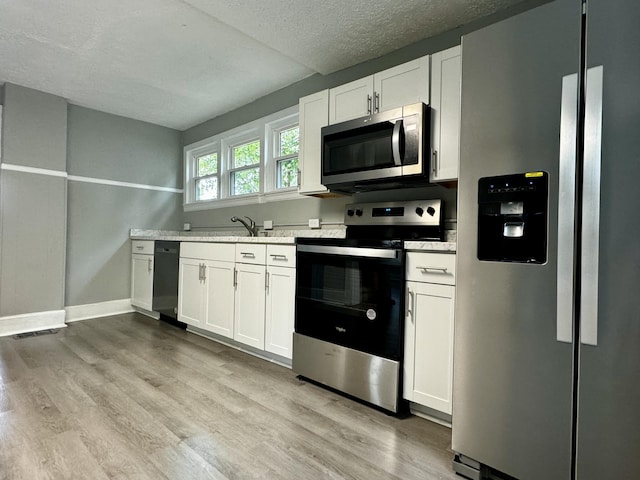 kitchen with a textured ceiling, white cabinetry, stainless steel appliances, and light hardwood / wood-style flooring