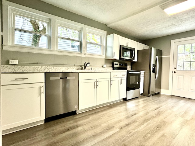 kitchen featuring stainless steel appliances, white cabinets, sink, and light wood-type flooring